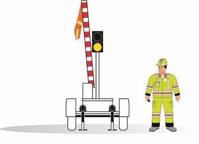 Barrière avec un feu jaune et le drapeau levé donnant l’ordre de circuler lentement.